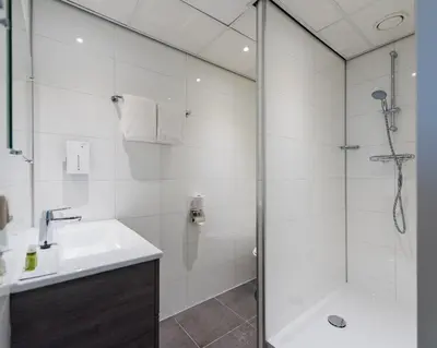 a bathroom with a shower and a sink and a tub at Tulip Inn Leiden Centre in Leiden