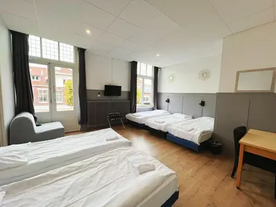 a room with four beds and a desk and a tv at CoronaZeist-Utrecht NL in Zeist