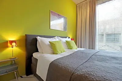a bedroom with a bed with green walls and a window at Eastendroom in Amsterdam