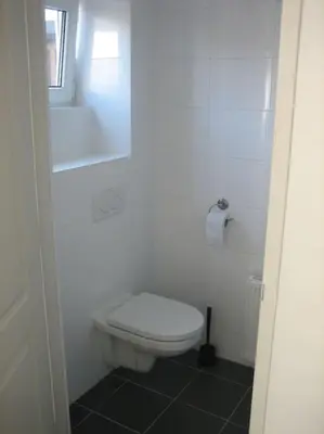a white bathroom with a toilet and a window at Modern zomerhuis voor 4 personen in Wijk aan Zee