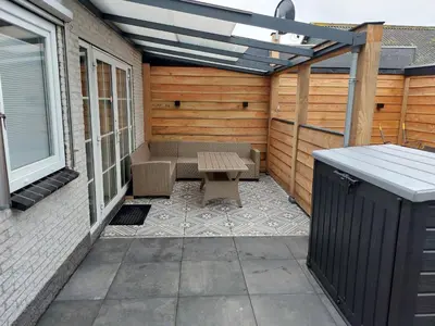 an outdoor patio with a bench and a solar roof at Modern zomerhuis voor 4 personen in Wijk aan Zee