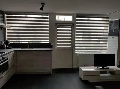 a kitchen with two windows and a television in it at Zomerhuisje 18K - 1 km van het strand in Wijk aan Zee