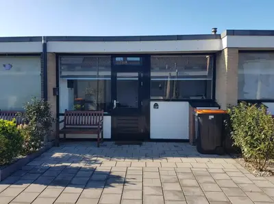 a bench sitting in front of a building at Zomerhuisje 18K - 1 km van het strand in Wijk aan Zee
