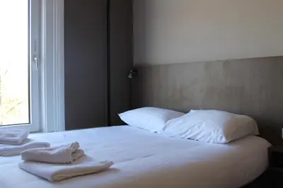 a bed with white sheets and pillows and a window at Aston City Hotel in Amsterdam