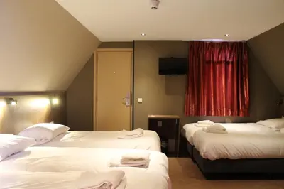 a hotel room with two beds and a red curtain at Aston City Hotel in Amsterdam