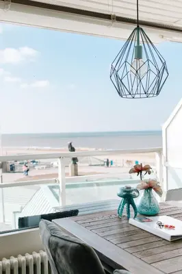 a dining room table with a view of the beach at Appartement Babette in Zandvoort