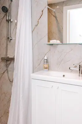 a bathroom with a white shower curtain and a sink at Appartement Babette in Zandvoort