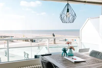 a dining room table with a view of the beach at Appartement Babette in Zandvoort