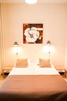 two beds in a bedroom with two lamps on the wall at Family Hotel Kooyk in Amsterdam