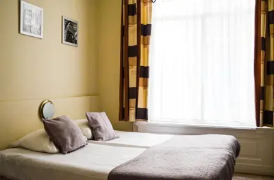 a bed sitting in a bedroom with a window at Family Hotel Kooyk in Amsterdam