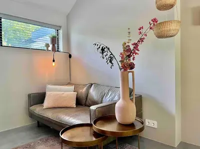 a living room with a couch and a vase with flowers at Duynbossie in Schoorl