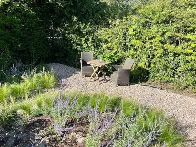 two chairs and a table in a garden at Duynbossie in Schoorl