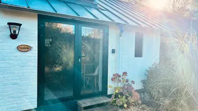a sliding glass door on a house with flowers at Duynbossie in Schoorl