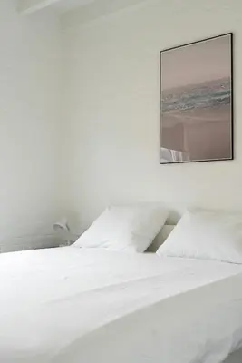 a bedroom with a white bed with a picture on the wall at -Casa Branca- nabij het meer, strand en keukenhof in Noordwijkerhout