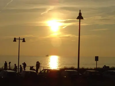 a sunset over the ocean with cars parked on the beach at Sterflat 39 in Egmond aan Zee