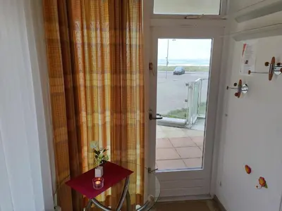 a door leading to a porch with a table and a window at Sterflat 39 in Egmond aan Zee