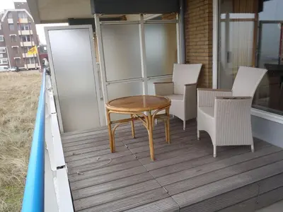 a wooden table and chairs on a balcony at Sterflat 39 in Egmond aan Zee