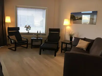 a living room with a couch and chairs and a window at Sterflat 45 in Egmond aan Zee