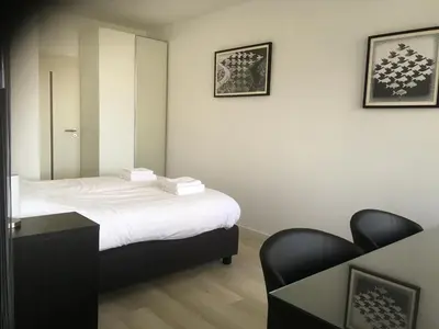 a bedroom with a bed with a mirror and a chair at Sterflat 45 in Egmond aan Zee