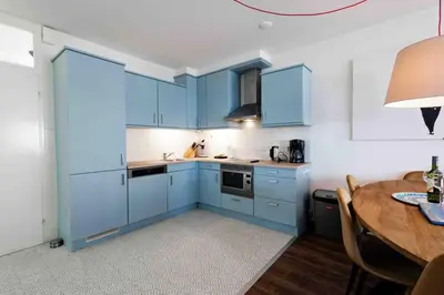 a kitchen with blue cabinets and a wooden table at Sterflat 53 in Egmond aan Zee