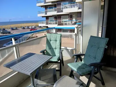 a table and chairs on a balcony with a view of the beach at Sterflat 53 in Egmond aan Zee