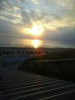 a sunset over the beach with the sun setting at Sterflat 53 in Egmond aan Zee
