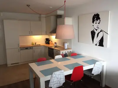 a kitchen with a dining room table with red chairs at Sterflat 53 in Egmond aan Zee