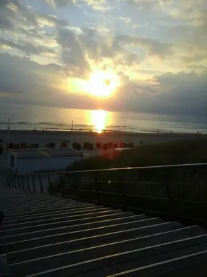a sunset over the beach with the sun setting at Sterflat 53 in Egmond aan Zee