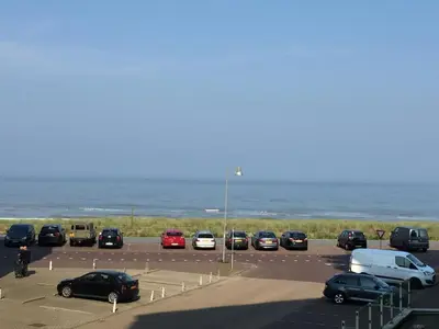 a parking lot with cars parked next to the ocean at Sterflat 53 in Egmond aan Zee