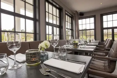 a dining room with tables and chairs with wine glasses at Fletcher Boutique Hotel Duinoord in Wassenaar