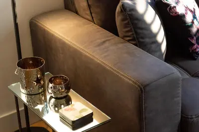 a brown leather chair with a side table with a cake at Spacious private apartement, 25min from Amsterdam in Hilversum