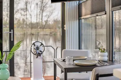a dining room with a table and a large window at Charming Tiny Houseboat Escape Near Amsterdam by Weltevreden Experience in Kortenhoef