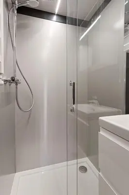 a white bathroom with a shower and a sink at Charming Tiny Houseboat Escape Near Amsterdam by Weltevreden Experience in Kortenhoef