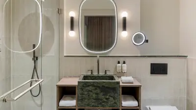 a bathroom with a sink and a mirror at The College Hotel Amsterdam, Autograph Collection in Amsterdam