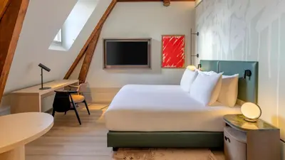 a hotel room with a bed and a desk at The College Hotel Amsterdam, Autograph Collection in Amsterdam