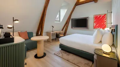 a hotel room with a large bed and a tv at The College Hotel Amsterdam, Autograph Collection in Amsterdam