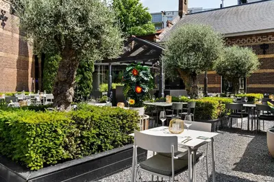 a patio with tables and chairs and trees at The College Hotel Amsterdam, Autograph Collection in Amsterdam