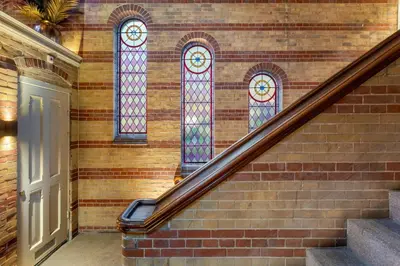 a staircase with two stained glass windows on a brick wall at The College Hotel Amsterdam, Autograph Collection in Amsterdam