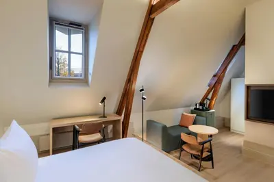 a bedroom with a bed and a desk and a tv at The College Hotel Amsterdam, Autograph Collection in Amsterdam