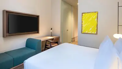 a hotel room with a bed and a tv and a chair at The College Hotel Amsterdam, Autograph Collection in Amsterdam