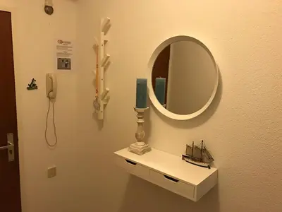 a mirror and a shelf with a candle and a phone at Sterflat 59 in Egmond aan Zee