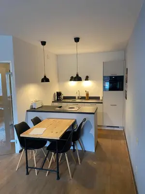 a kitchen with a table and some chairs and a counter at Sterflat 59 in Egmond aan Zee