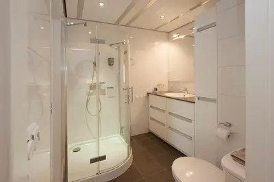 a bathroom with a shower and a toilet and a sink at Sterflat 61 in Egmond aan Zee