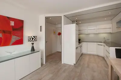 a kitchen with white cabinets and a red painting on the wall at Sterflat 61 in Egmond aan Zee