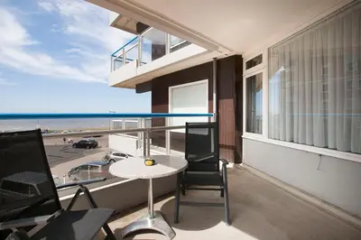 a balcony with a table and a view of the beach at Sterflat 61 in Egmond aan Zee