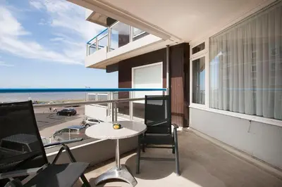 a balcony with a table and a view of the beach at Sterflat 61 in Egmond aan Zee