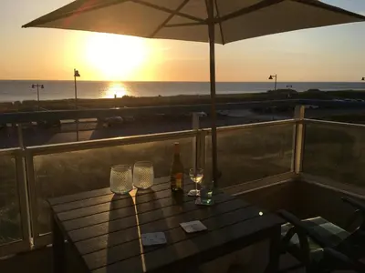 a table with wine glasses and an umbrella on the beach at Sterflat 65 in Egmond aan Zee