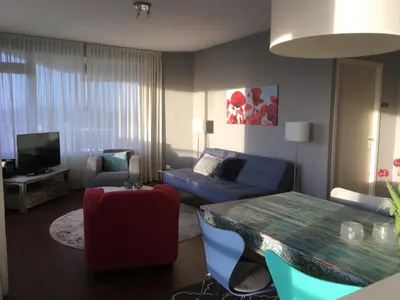 a living room with a blue couch and a table at Sterflat 65 in Egmond aan Zee