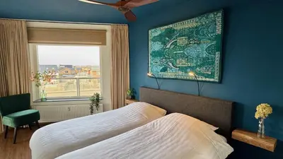 a bedroom with a large bed and a window at Sterflat 65 in Egmond aan Zee