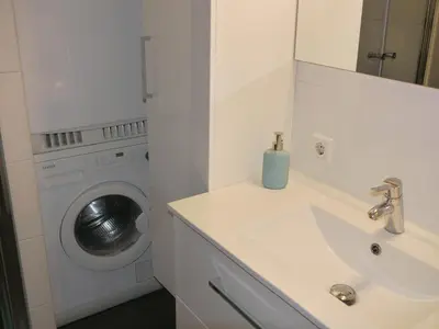 a bathroom with a sink and a washing machine at Sterflat 65 in Egmond aan Zee